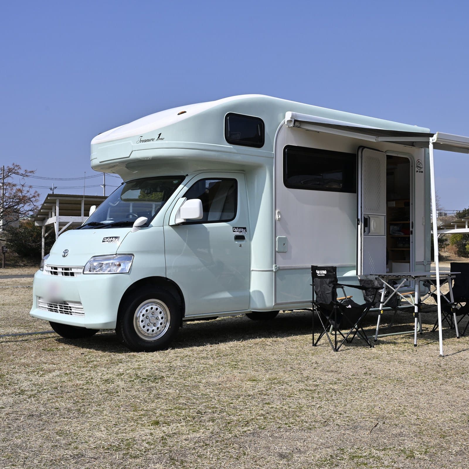 キャンプ場でオーニングを広げ、テーブルとチェアを並べた JP STAR Treasure 1